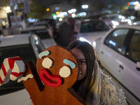 A young Iranian woman poses for a photograph while holding a Christmas accessory during Christmas shopping in downtown Tehran, Iran, on Dece...