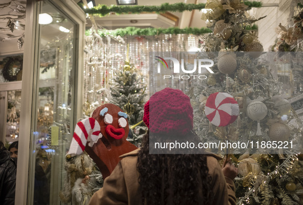 A young Iranian woman poses for a photograph in front of a shop window decorated for Christmas shopping while holding Christmas accessories...