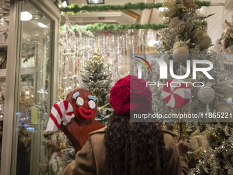 A young Iranian woman poses for a photograph in front of a shop window decorated for Christmas shopping while holding Christmas accessories...