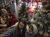 Young Iranian women stand together in front of Christmas trees that are placed outside a shop decorated for Christmas shopping in downtown T...