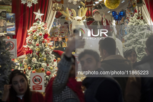 An Iranian couple takes a selfie in front of a shop window that is decorated for Christmas shopping in downtown Tehran, Iran, on December 13...