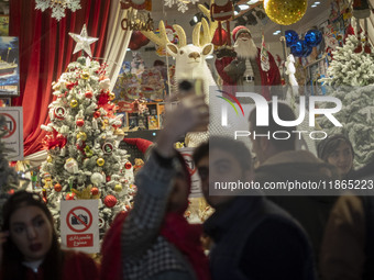 An Iranian couple takes a selfie in front of a shop window that is decorated for Christmas shopping in downtown Tehran, Iran, on December 13...