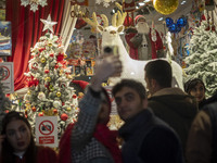 An Iranian couple takes a selfie in front of a shop window that is decorated for Christmas shopping in downtown Tehran, Iran, on December 13...