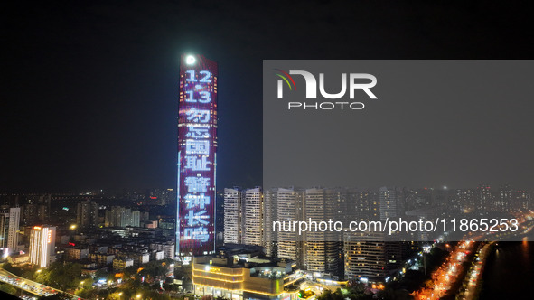 A large LED screen on the exterior wall of a building displays a propaganda slogan to commemorate the innocent victims of the Nanjing Massac...