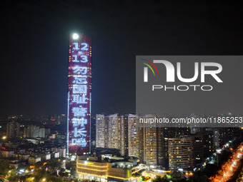 A large LED screen on the exterior wall of a building displays a propaganda slogan to commemorate the innocent victims of the Nanjing Massac...