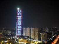 A large LED screen on the exterior wall of a building displays a propaganda slogan to commemorate the innocent victims of the Nanjing Massac...