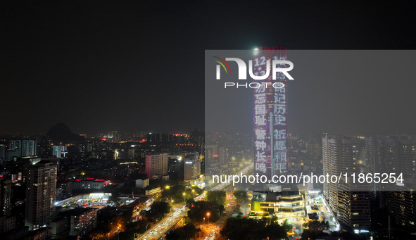 A large LED screen on the exterior wall of a building displays a propaganda slogan to commemorate the innocent victims of the Nanjing Massac...