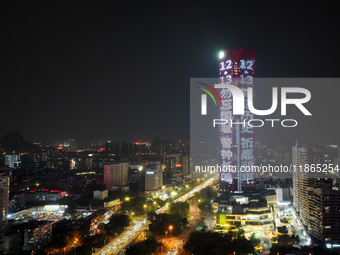 A large LED screen on the exterior wall of a building displays a propaganda slogan to commemorate the innocent victims of the Nanjing Massac...