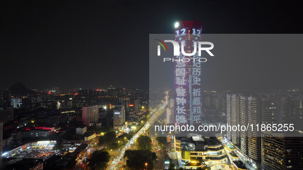 A large LED screen on the exterior wall of a building displays a propaganda slogan to commemorate the innocent victims of the Nanjing Massac...