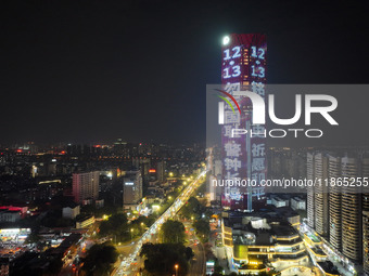 A large LED screen on the exterior wall of a building displays a propaganda slogan to commemorate the innocent victims of the Nanjing Massac...