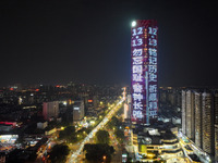 A large LED screen on the exterior wall of a building displays a propaganda slogan to commemorate the innocent victims of the Nanjing Massac...