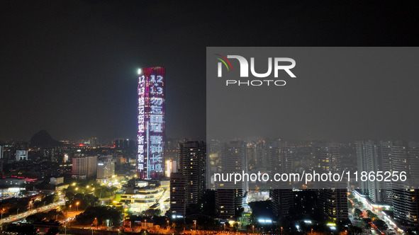 A large LED screen on the exterior wall of a building displays a propaganda slogan to commemorate the innocent victims of the Nanjing Massac...