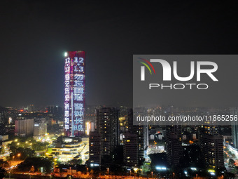 A large LED screen on the exterior wall of a building displays a propaganda slogan to commemorate the innocent victims of the Nanjing Massac...