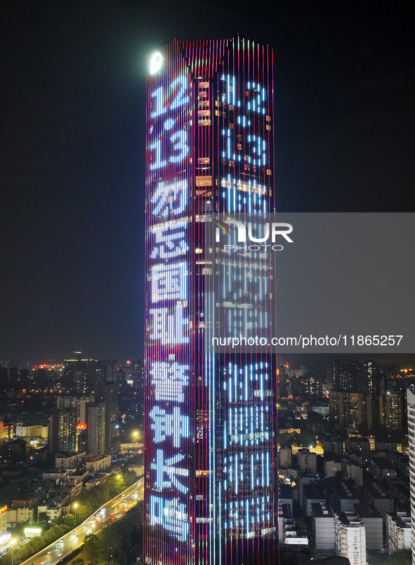 A large LED screen on the exterior wall of a building displays a propaganda slogan to commemorate the innocent victims of the Nanjing Massac...