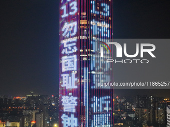 A large LED screen on the exterior wall of a building displays a propaganda slogan to commemorate the innocent victims of the Nanjing Massac...