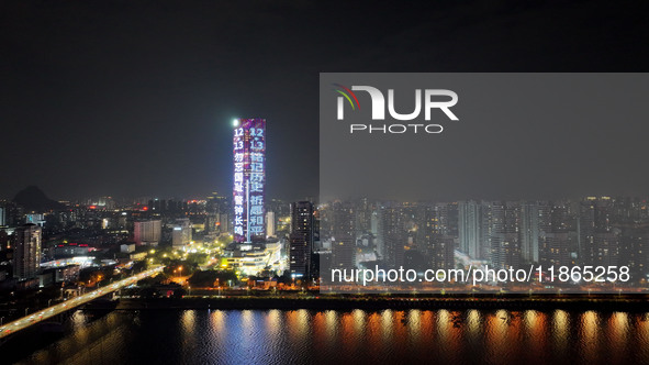 A large LED screen on the exterior wall of a building displays a propaganda slogan to commemorate the innocent victims of the Nanjing Massac...