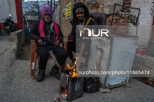 Key makers from the Sikh community warm themselves by a bonfire during a cold winter day in Baramulla, Jammu and Kashmir, India, on December...