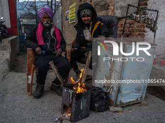 Key makers from the Sikh community warm themselves by a bonfire during a cold winter day in Baramulla, Jammu and Kashmir, India, on December...