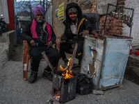 Key makers from the Sikh community warm themselves by a bonfire during a cold winter day in Baramulla, Jammu and Kashmir, India, on December...