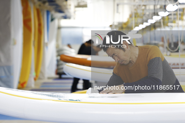 A worker produces surfboards for export to Europe and the United States at a production workshop in Suqian, Jiangsu province, China, on Dece...