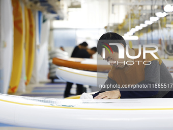 A worker produces surfboards for export to Europe and the United States at a production workshop in Suqian, Jiangsu province, China, on Dece...