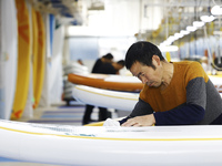 A worker produces surfboards for export to Europe and the United States at a production workshop in Suqian, Jiangsu province, China, on Dece...