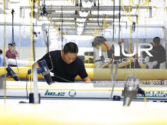 Workers produce surfboards for export to Europe and the United States at a production workshop in Suqian, Jiangsu province, China, on Decemb...