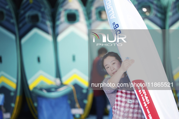 A worker produces surfboards for export to Europe and the United States at a production workshop in Suqian, Jiangsu province, China, on Dece...