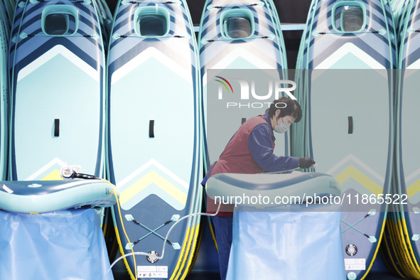 A worker produces surfboards for export to Europe and the United States at a production workshop in Suqian, Jiangsu province, China, on Dece...