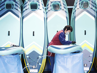 A worker produces surfboards for export to Europe and the United States at a production workshop in Suqian, Jiangsu province, China, on Dece...