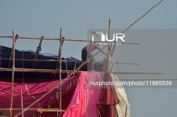 A worker works on a semi-finished tent set up on the rooftop of a building in Siliguri, India, on December 14, 2024. 