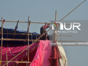 A worker works on a semi-finished tent set up on the rooftop of a building in Siliguri, India, on December 14, 2024. (