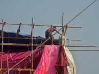 A worker works on a semi-finished tent set up on the rooftop of a building in Siliguri, India, on December 14, 2024. (