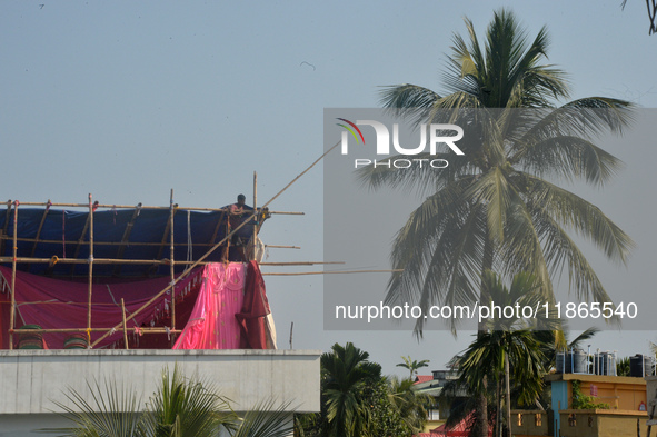 A worker works on a semi-finished tent set up on the rooftop of a building in Siliguri, India, on December 14, 2024. 