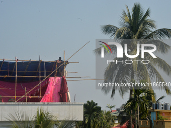 A worker works on a semi-finished tent set up on the rooftop of a building in Siliguri, India, on December 14, 2024. (