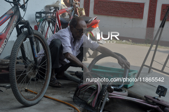 An elderly cycle repair mechanic repairs a bicycle tire in Siliguri, India, on December 14, 2024. In modern times of bikes and vehicles, the...