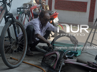 An elderly cycle repair mechanic repairs a bicycle tire in Siliguri, India, on December 14, 2024. In modern times of bikes and vehicles, the...