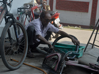 An elderly cycle repair mechanic repairs a bicycle tire in Siliguri, India, on December 14, 2024. In modern times of bikes and vehicles, the...