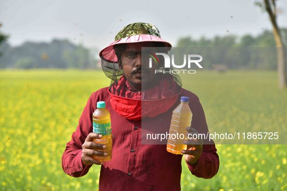 A beekeeper shows raw honey at a honeybee farm near a mustard field in Morigaon district, Assam, India, on December 9, 2024. 