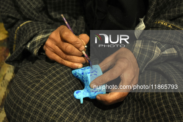 In Srinagar, Kashmir, India, on December 14, 2024, a Kashmiri artisan paints Christmas gift items at the workshop before sending them to the...