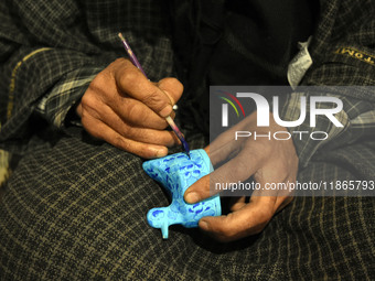 In Srinagar, Kashmir, India, on December 14, 2024, a Kashmiri artisan paints Christmas gift items at the workshop before sending them to the...