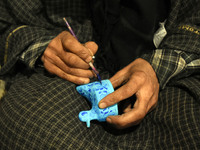 In Srinagar, Kashmir, India, on December 14, 2024, a Kashmiri artisan paints Christmas gift items at the workshop before sending them to the...