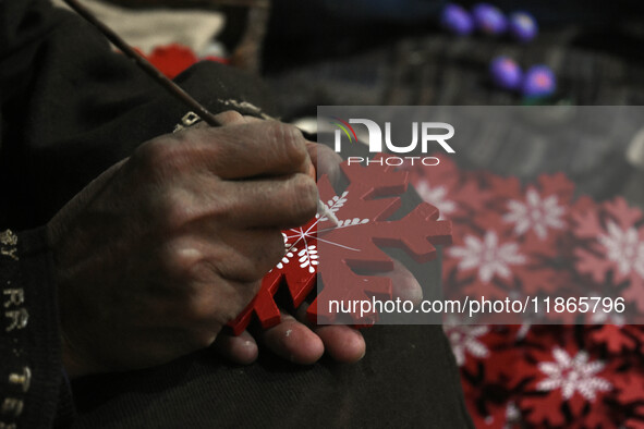 In Srinagar, Kashmir, India, on December 14, 2024, a Kashmiri artisan paints Christmas gift items at the workshop before sending them to the...