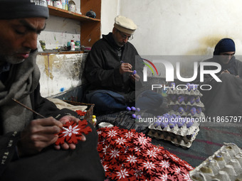 In Srinagar, Kashmir, India, on December 14, 2024, Kashmiri artisan Muhammad Akhtar Mir paints Christmas gift items at his workshop before s...