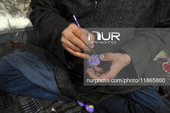 In Srinagar, Kashmir, India, on December 14, 2024, Kashmiri artisan Muhammad Akhtar Mir paints Christmas gift items at his workshop ahead of...