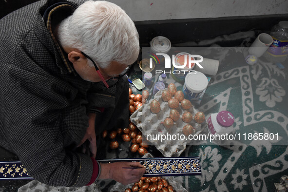 In Srinagar, Kashmir, India, on December 14, 2024, a Kashmiri artisan paints Christmas gift items at the workshop before sending them to the...