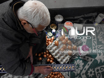 In Srinagar, Kashmir, India, on December 14, 2024, a Kashmiri artisan paints Christmas gift items at the workshop before sending them to the...