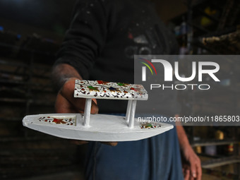 In Srinagar, Kashmir, India, on December 14, 2024, a Kashmiri artisan displays a Christmas ornament at the workshop before sending it to the...