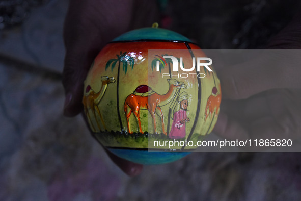 In Srinagar, Kashmir, India, on December 14, 2024, a Kashmiri artisan shows a Christmas bauble at the workshop before sending it to the mark...