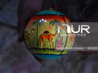 In Srinagar, Kashmir, India, on December 14, 2024, a Kashmiri artisan shows a Christmas bauble at the workshop before sending it to the mark...